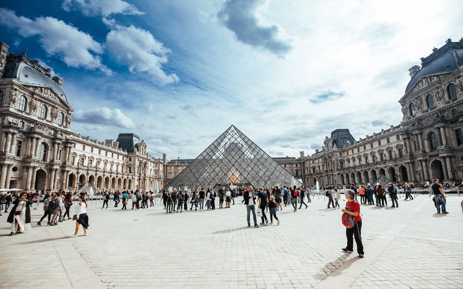 personnes marchant devant le musée du Louvre